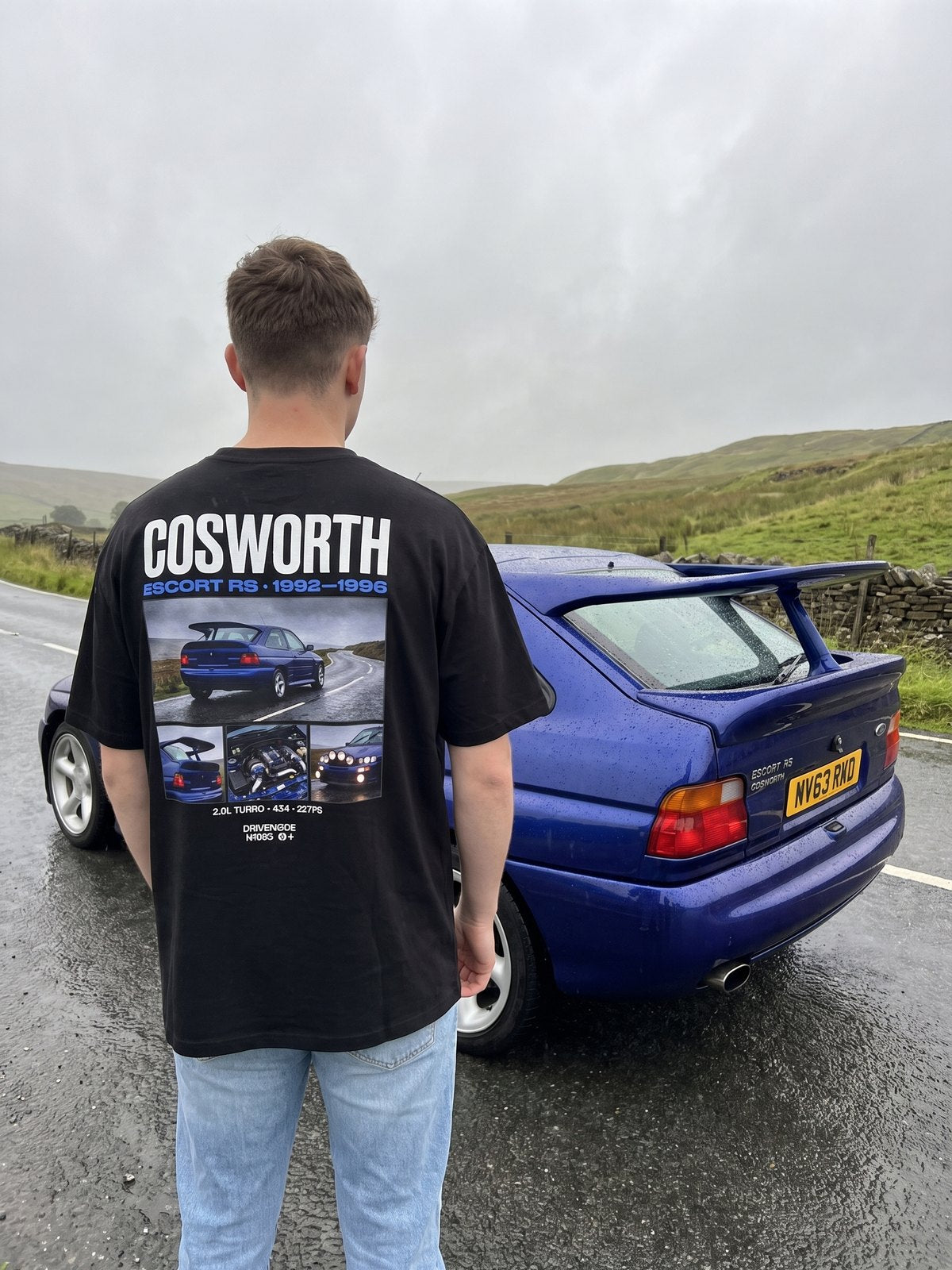 T-shirt oversize Escort Cosworth noir porté de dos devant la voiture