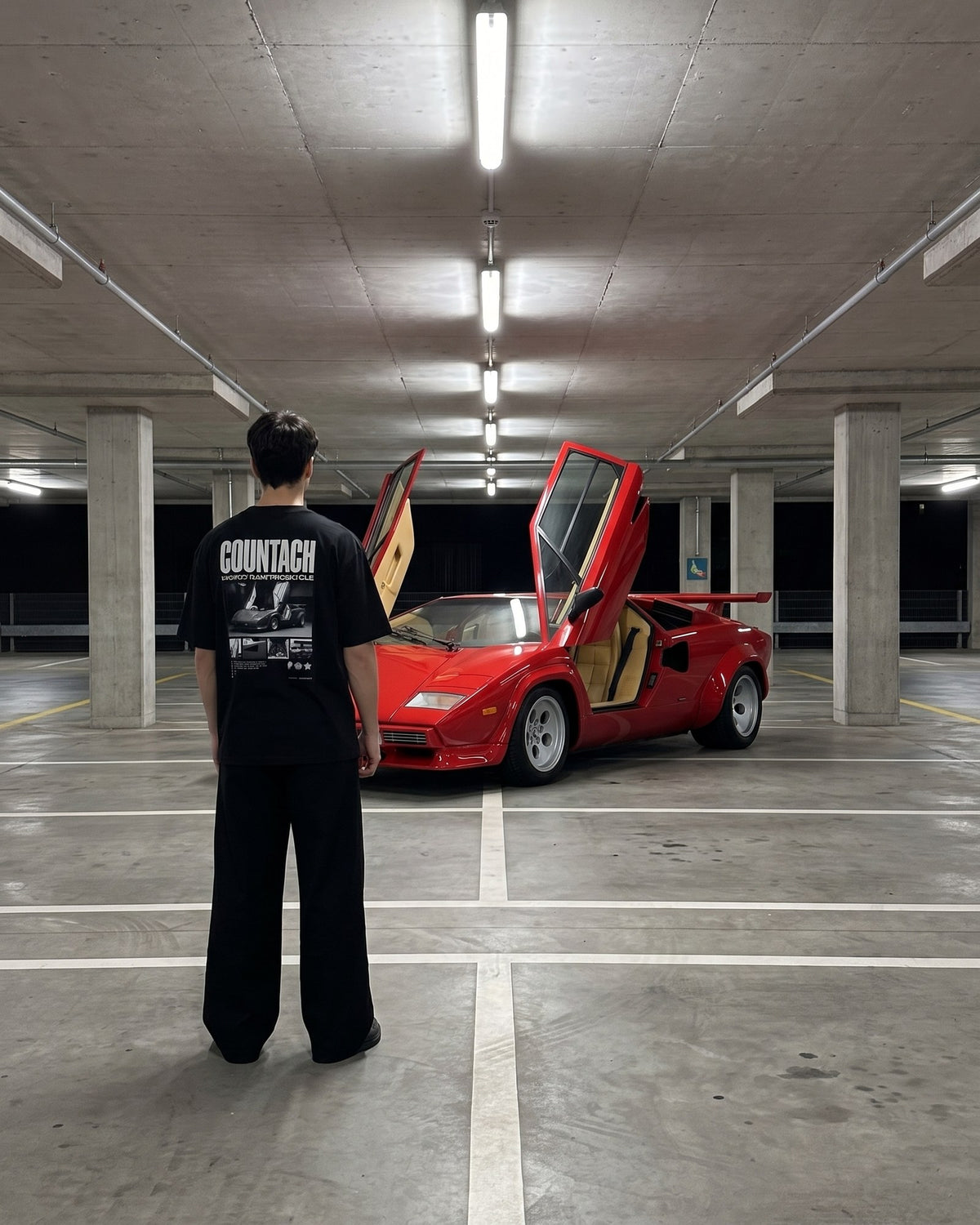 T-shirt oversize Countach porté de dos devant une Lamborghini Countach rouge dans un parking souterrain