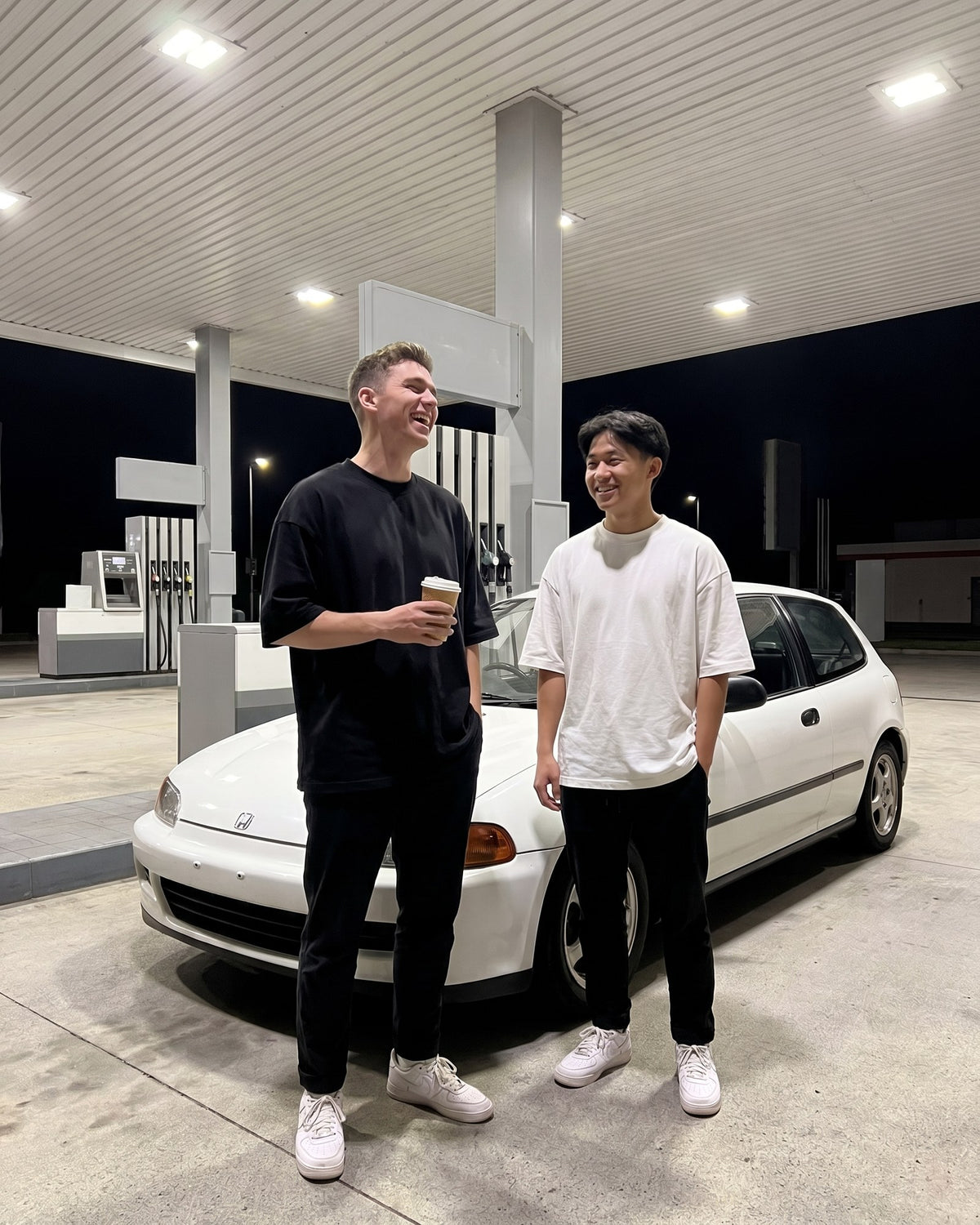 Deux amis en t-shirts oversize noir et blanc à une station-service de nuit