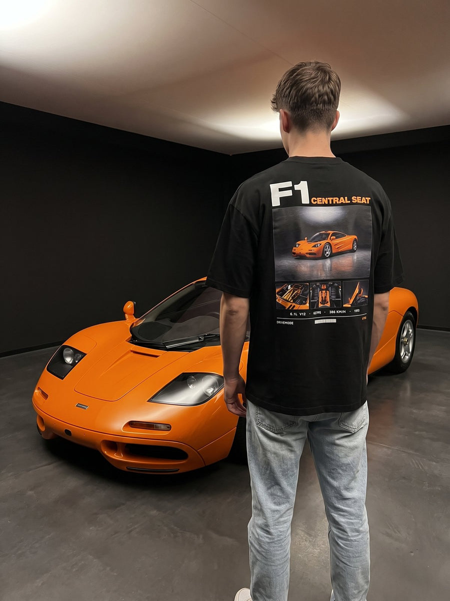T-shirt oversize McLaren F1 noir porté de dos devant la voiture
